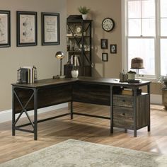 a corner desk with two drawers in front of a window and pictures on the wall