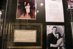 framed photos and letters are on display in a museum case, including an autographed couple