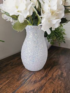 white flowers in a glitter vase on a wooden table