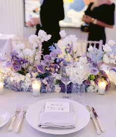 the table is set with white and purple flowers