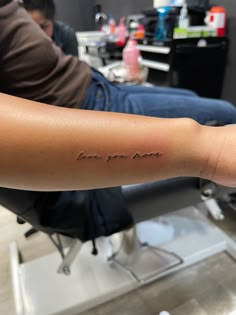 a person sitting in a chair with a tattoo on their arm that says, love you mom