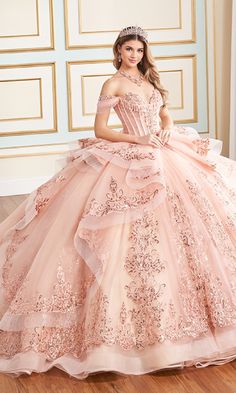 Glitter tulle quinceanera dress with an off-the-shoulder neckline, lace applique, stone accents, and covered buttons down the front of the corset bodice. This quinceanera ball gown features draped off-the-shoulder straps and a semi-sheer bodice.