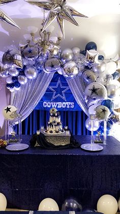 a table topped with balloons and cake next to a blue stage set up for a cowboys party