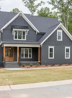 a gray house with white trim and two story windows on the second floor is shown