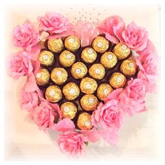 a heart shaped box filled with chocolates and pink flowers