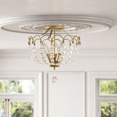 a chandelier hanging from the ceiling in a room with white walls and windows