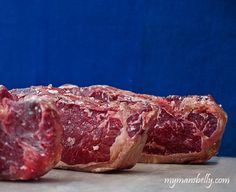 two pieces of raw meat sitting on top of a counter next to each other with blue background