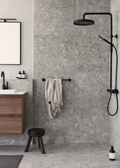 a black and white photo of a bathroom with a shower head, towel hanging on the wall