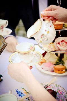 two people sitting at a table with tea cups and saucers