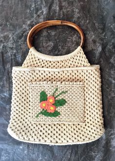 Adorable vintage macrame bag that is simple and sweet.  Details include: The body is ivory with a floral applique in a peachy pink, yellow and green The floral applique is on a patch pocket on one side of the bag that measures 7 inches wide by 5 1/4 inches tall Fully lined in ivory colored guaze fabric One small 4 1/4 inch by 5 1/4 inch pocket sewn into the lining Oval top handle made of bamboo Makers label is MCL Made in the Phillippines I believe that it was made in the 1970's The condition is Vintage Beige Crochet Bag For Summer, Vintage Crochet Bag For Spring, Vintage Crochet Beach Bag For Spring, Vintage Natural Crochet Bag, Beige Vintage Crochet Bags, Beige Crochet Macrame Bag For Spring, Vintage Crochet Beach Bag, Vintage Beige Crochet Bags, Vintage Crochet Shoulder Bag For Summer