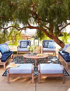 a patio with blue and white furniture under a tree