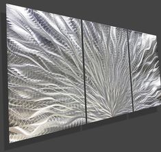 three metal wall art pieces on a gray background