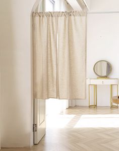 an open door leading to a bedroom with white walls and flooring, along with a mirror on the wall