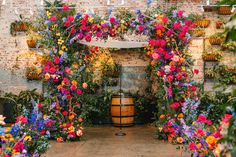 an outdoor ceremony with colorful flowers and vines on the wall, along with wooden barrels