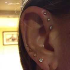 a close up of a person's ear with three different piercings on it