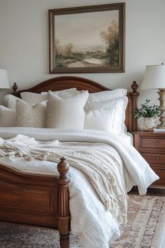 a bed with white linens and pillows in a bedroom next to a painting on the wall