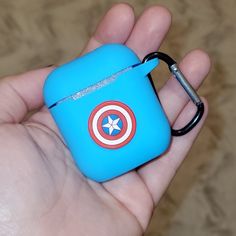 a hand holding a blue case with a captain's shield on the side and a keychain attached to it