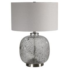 a glass table lamp with a white shade on the base and a silver metal base