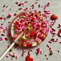 a lollipop filled with sprinkles and hearts on top of a table