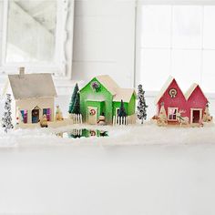 a group of small houses sitting on top of a counter next to a mirror and christmas tree