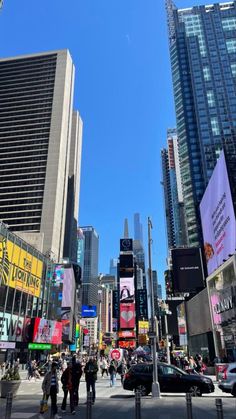 people are walking around in the city with tall buildings and billboards on both sides