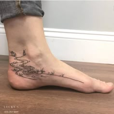 a woman's foot with a river and birds tattoo on the side of her leg