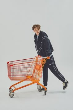 a young man pushing a shopping cart with an orange basket on it's wheels