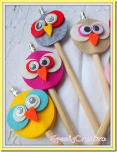 four colorful owls are sitting on top of wooden sticks