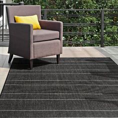 a gray chair sitting on top of a wooden floor next to a black and white rug