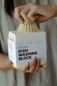 a woman holding a box of dish washing block with her hands on top of it