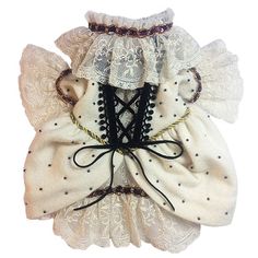 a white dress with black lace and bows on the neckline is displayed against a white background