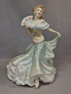 a ceramic figurine is holding a fan