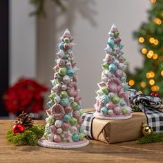 two small christmas trees sitting on top of a wooden table next to a present box