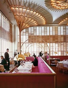 people sitting at tables in a restaurant with large windows and wooden ceilinging above them