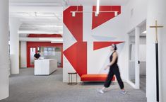 a woman walking through an office with red and white walls