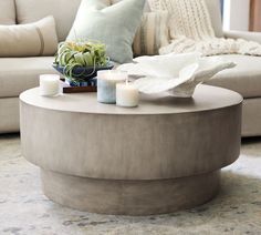 a coffee table with candles on it in front of a couch and pillows behind it