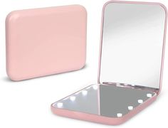 a pink vanity mirror sitting on top of a white counter next to a small box