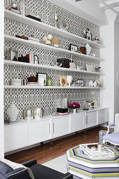 a living room filled with lots of furniture and shelves covered in wall coverings next to a window