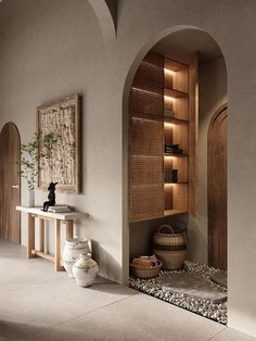 an arched doorway leads to a bathroom with stone flooring and built - in shelving