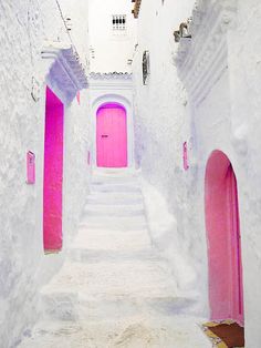 an alley way with white walls and blue doors