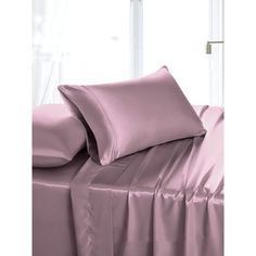 a bed with pink sheets and pillows in front of a window