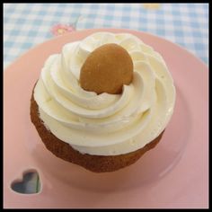 a cupcake with white frosting on a pink plate