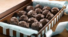 a box filled with chocolate covered donuts sitting on top of a wooden table next to a blue ribbon