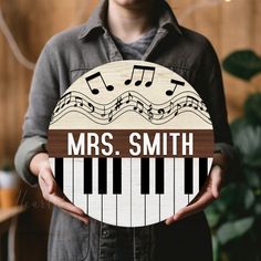 a person holding a wooden sign with musical notes on it that says, mrs smith