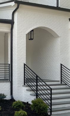 a white brick building with black railing and stairs