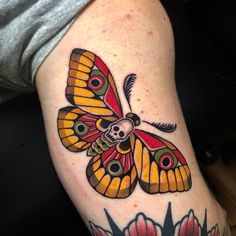 a colorful butterfly tattoo on the left arm and leg, with flowers around it's edges