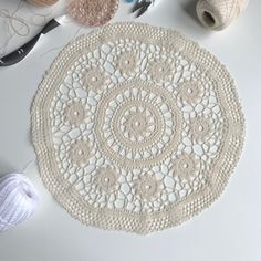 a crocheted doily sits on a table next to yarn and scissors