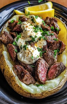 a plate with some meat and potatoes on it next to lemon wedges, fork and knife