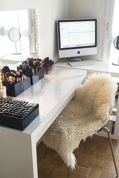 a white desk with a computer, mirror and other items on it in front of a window