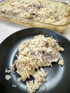 a black plate topped with food next to a casserole dish filled with rice